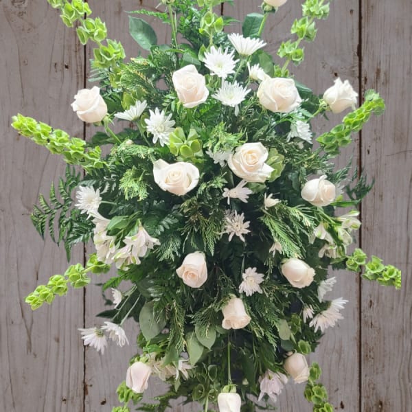 White roses and daisies arranged with green spikes in a starburst design