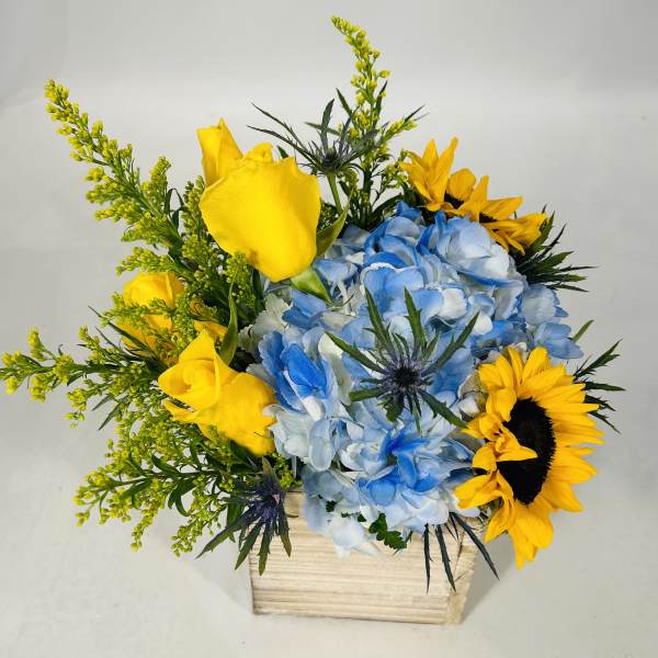 Yellow roses and sunflowers with blue hydrangeas in a wooden box