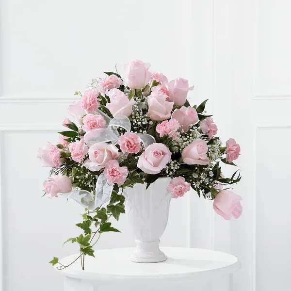 Pink roses and carnations arranged in a white vase