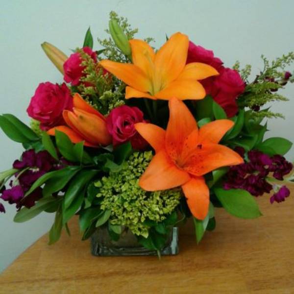 Orange lilies and pink roses in a glass vase