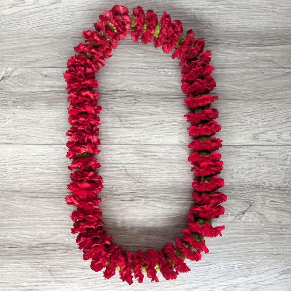 Red carnation lei arranged in an oval shape on a wood surface