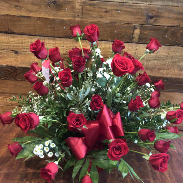Large bouquet of red roses with greenery and a red ribbon