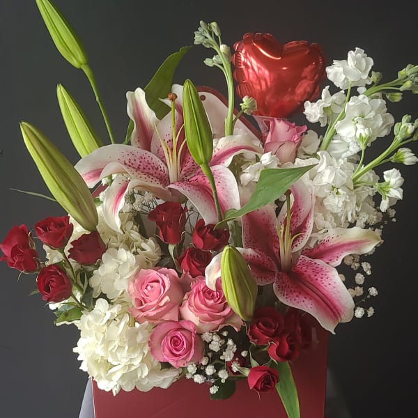 Bouquet of pink lilies and red and pink roses in a red box with a heart balloon