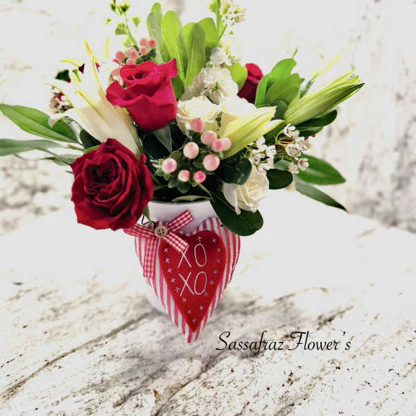 Bouquet of red and white roses in a white vase with a red heart tag