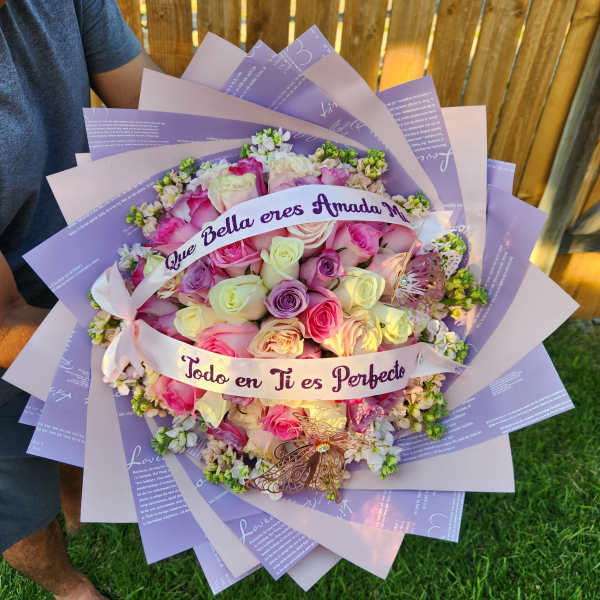 Bouquet of pastel roses wrapped in lavender paper with a ribbon