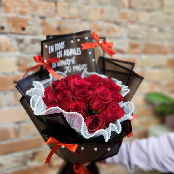 Bouquet of red roses wrapped in black paper with red ribbons