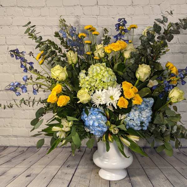 Large mixed flower arrangement in a white pedestal vase
