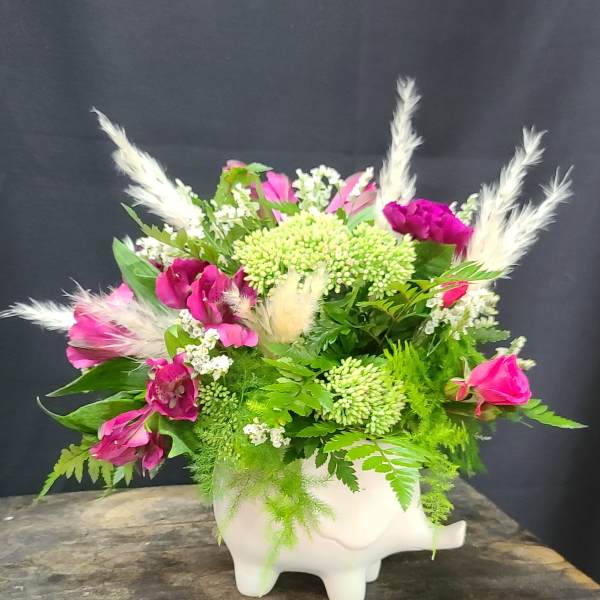 Pink and white floral arrangement in a white pig-shaped vase