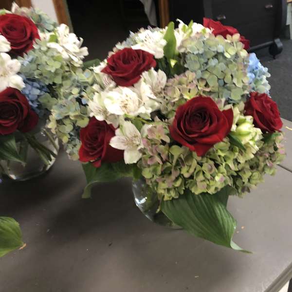 Bouquet of red roses and white flowers with blue hydrangeas in a glass vase