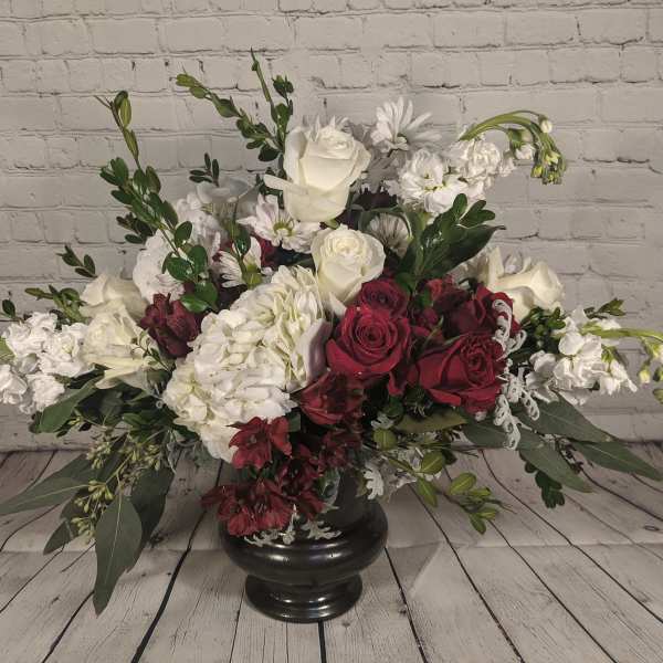 Large floral arrangement of white and deep red flowers in a black vase