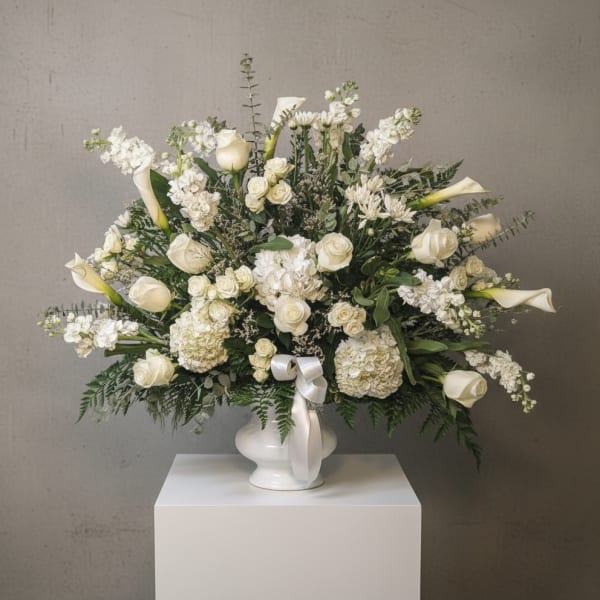 White floral arrangement with roses, calla lilies, and hydrangeas in a white vase