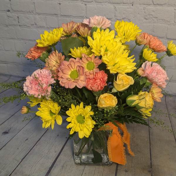 Bouquet of yellow and peach flowers in a clear glass vase