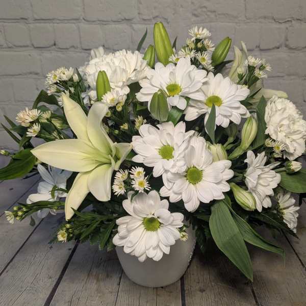 White lilies and daisies arranged in a white vase