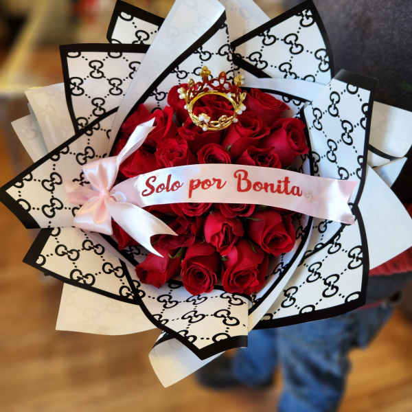 Bouquet of red roses wrapped in black-and-white patterned paper with a pink ribbon