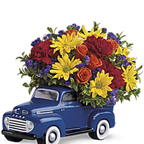 Blue truck figurine filled with colorful flowers
