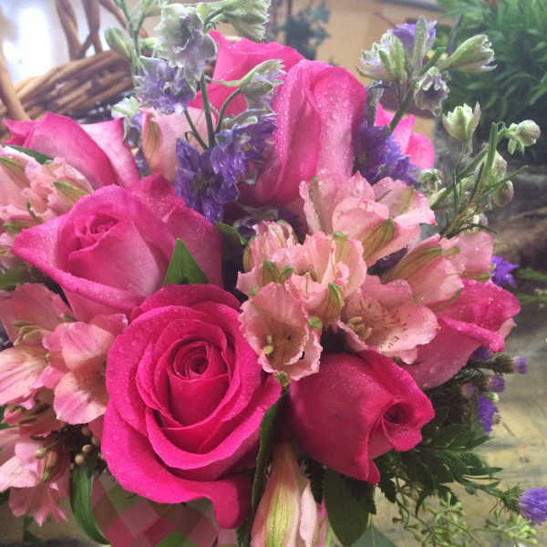 Pink roses and pale pink flowers with purple accents in a hand-tied bouquet