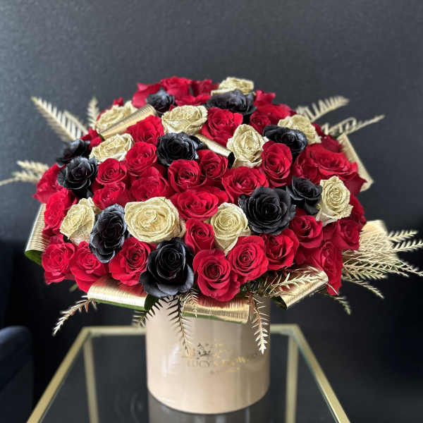 Bouquet of red, black, and gold roses in a round box