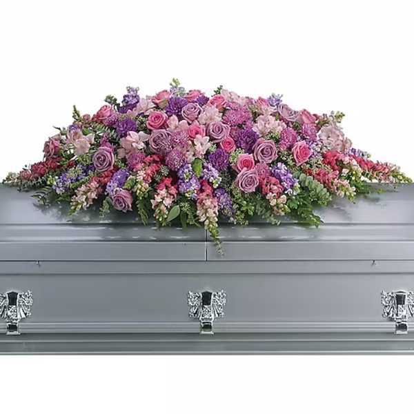 Lavender and pink floral casket spray on a gray casket