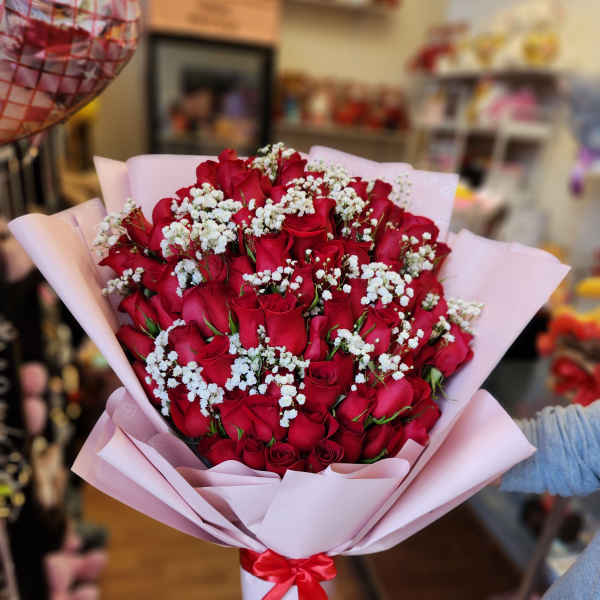 Bouquet of red roses with white baby's breath in pink wrapping