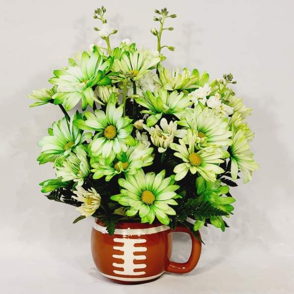 Green and white daisy bouquet in a football-shaped mug vase