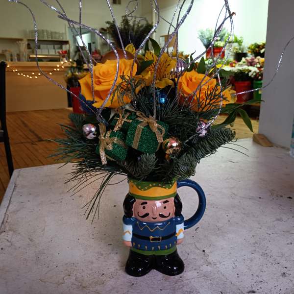Orange roses in a festive mug with glittery branches and ribbon