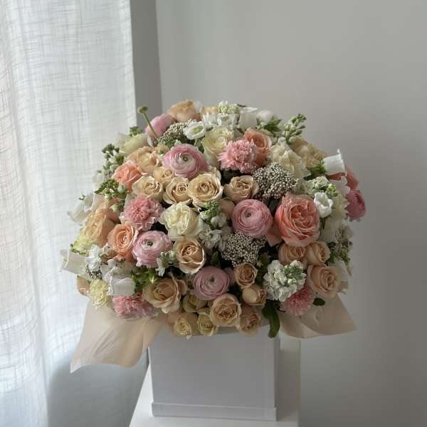 Large pastel bouquet of roses, ranunculus, and carnations in a white box