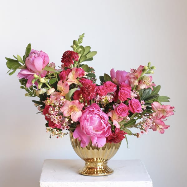 Pink floral arrangement in a gold vase