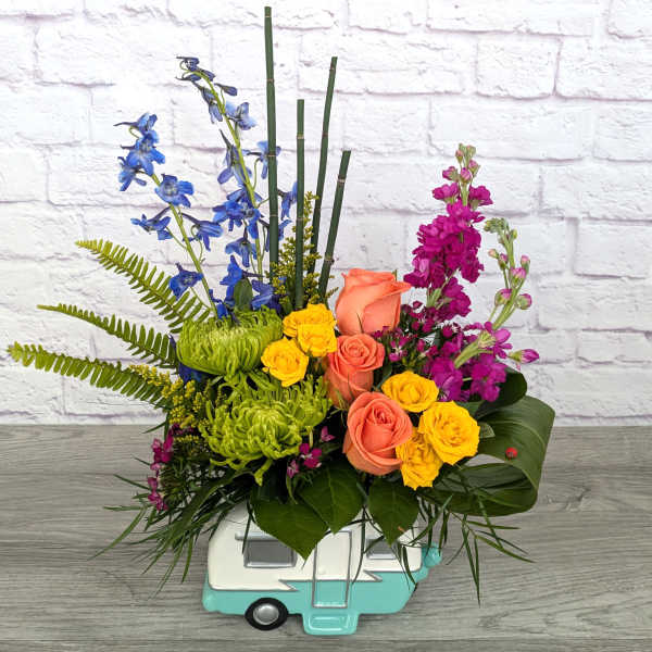 Colorful floral arrangement in a turquoise camper-shaped container