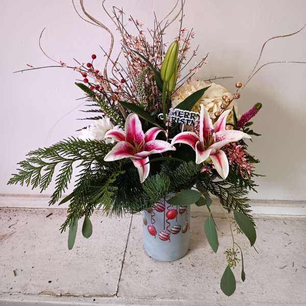 Holiday floral arrangement with pink lilies in a decorated container