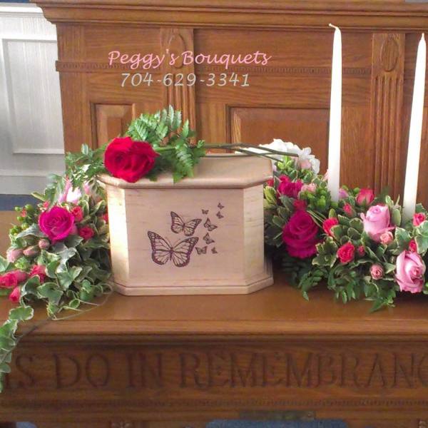 Casket spray with pink and white roses around a butterfly urn