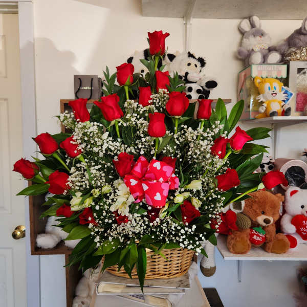 Basket arrangement of red roses with white baby's breath and a pink heart ribbon