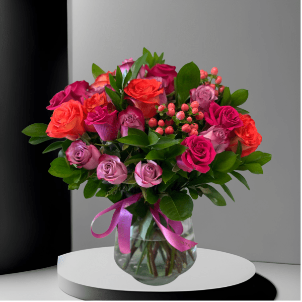 Bouquet of pink and orange roses in a glass vase with a ribbon