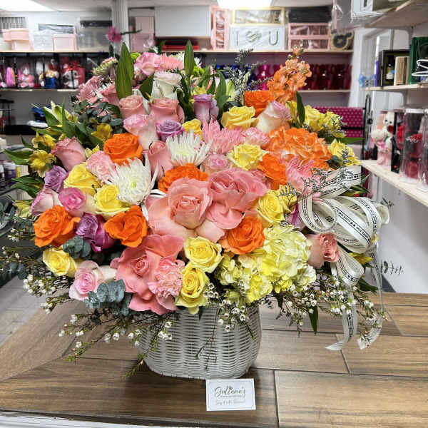 Large mixed bouquet of pink, yellow, orange, and white flowers in a white basket