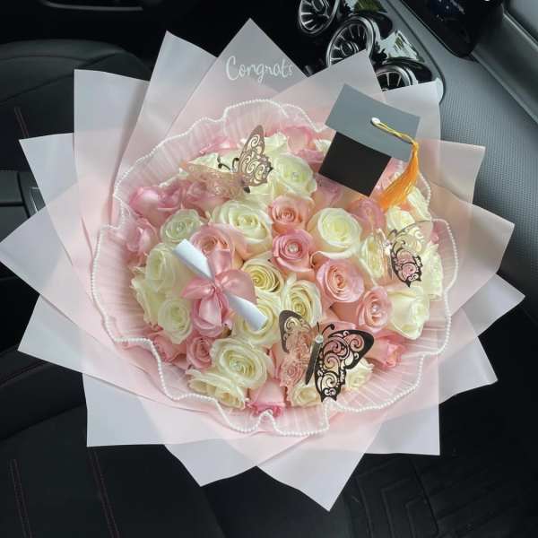 Pink and cream rose bouquet with butterfly decorations and a graduation cap topper