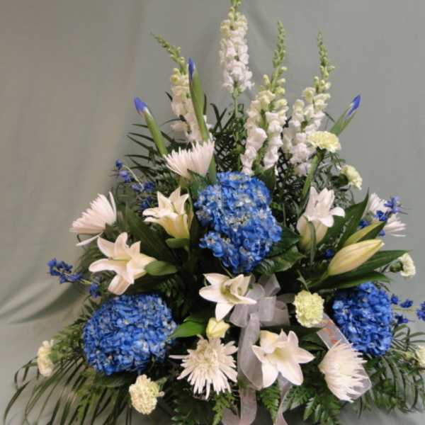 Blue hydrangeas and white lilies in a tall floral arrangement