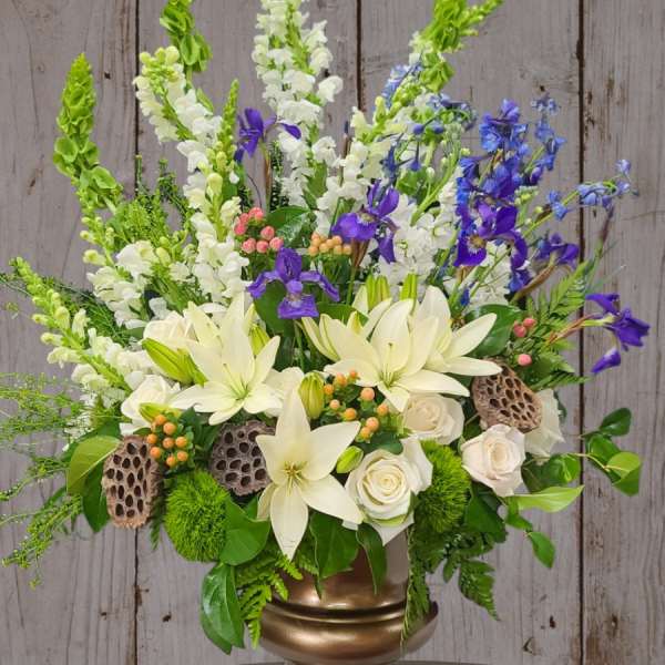 White lilies and roses with purple and blue flowers in a gold vase