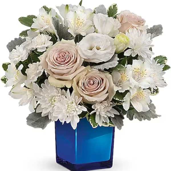 Bouquet of white and blush flowers in a blue glass vase