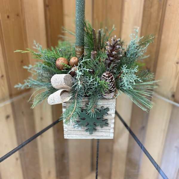 Small evergreen candle arrangement in a wooden box with pinecones and a teal taper candle
