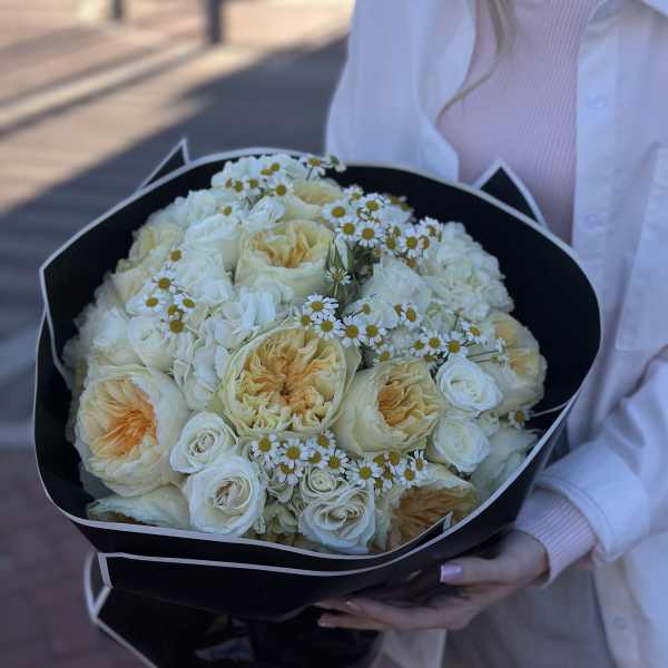 Bouquet of cream roses and small white daisies wrapped in black paper