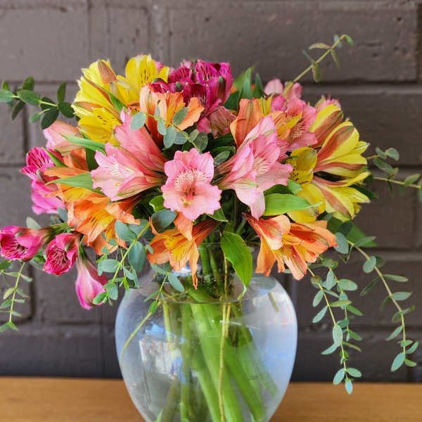 Bouquet of pink, yellow, and orange alstroemeria in a glass vase