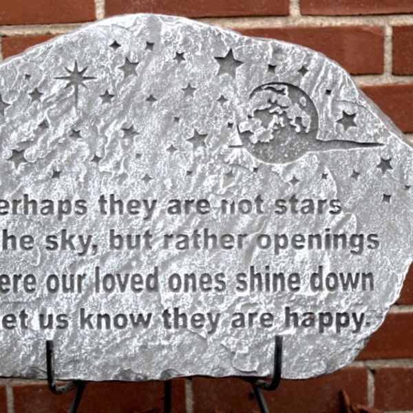 Decorative memorial stone plaque with a starry quote on a brick wall