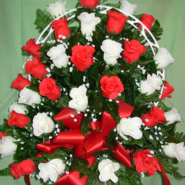 Red and white rose arrangement with a red ribbon on a white stand