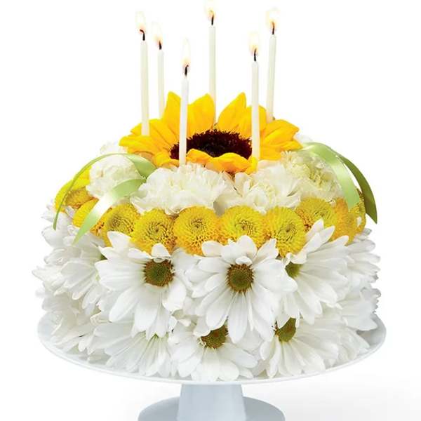 Daisy and sunflower cake with lit candles on a pedestal stand