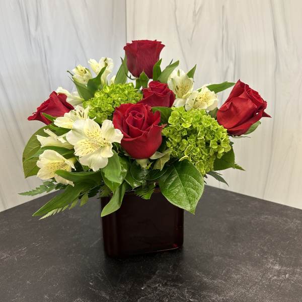 Red roses and white alstroemeria in a dark glass vase