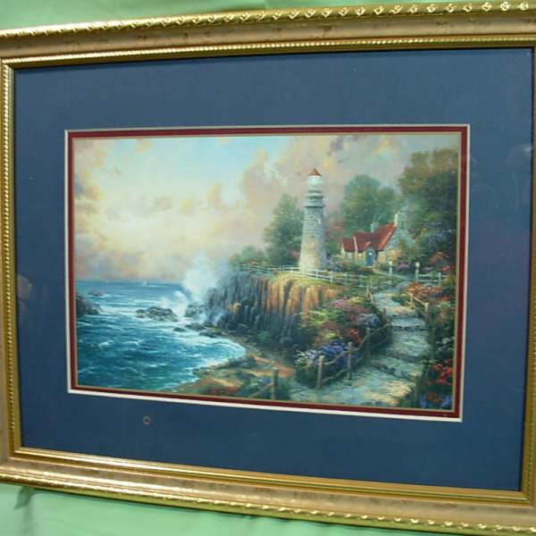 Framed lighthouse landscape painting on a blue mat