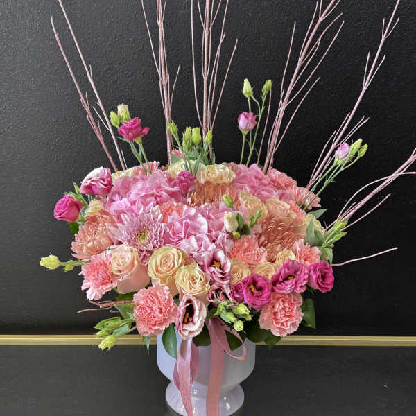 Pink and cream mixed bouquet in a white vase with tall decorative branches