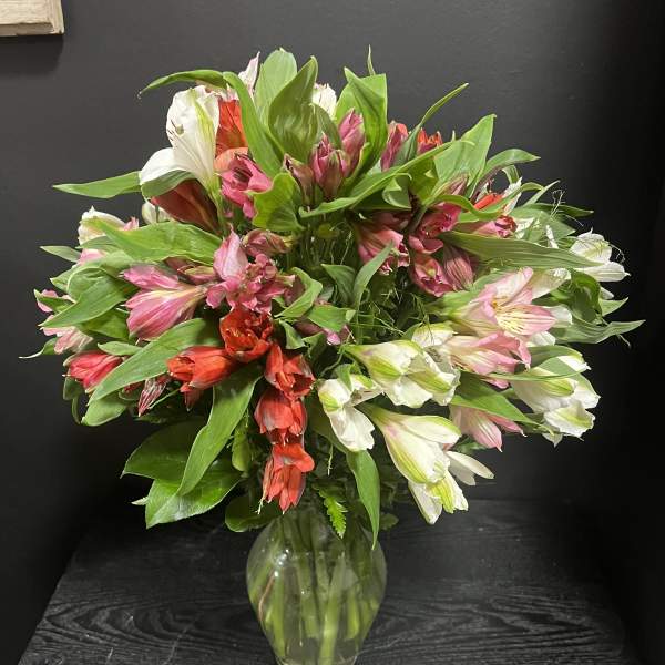 Mixed pink, white, and red flowers in a clear glass vase