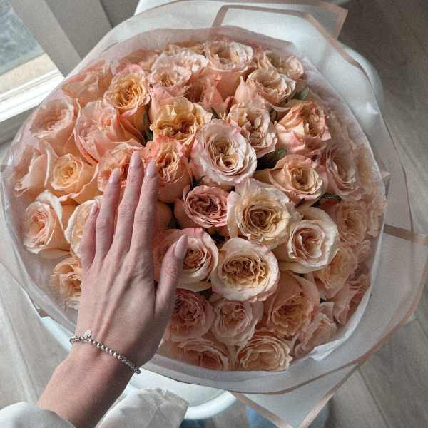 Large bouquet of peach roses wrapped in translucent paper