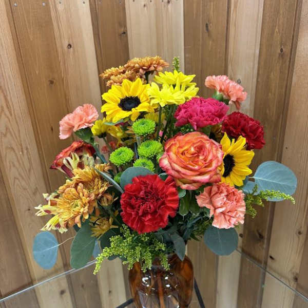 Mixed bouquet of bright flowers in an amber glass vase