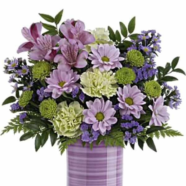 Lavender and green floral arrangement in a purple vase